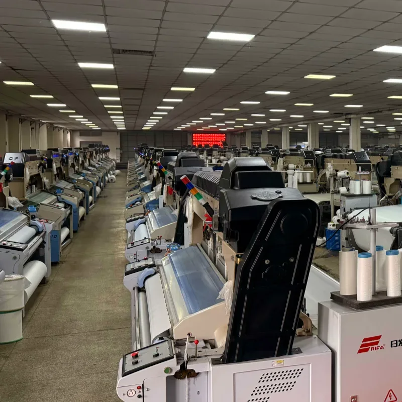 HOME Large textile manufacturing mill featuring rows of automated industrial weaving looms stretching down a long factory floor