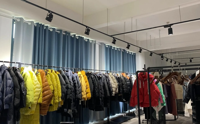 Custom outerwear showroom featuring colorful padded jackets and outdoor coats on display clothing racks.