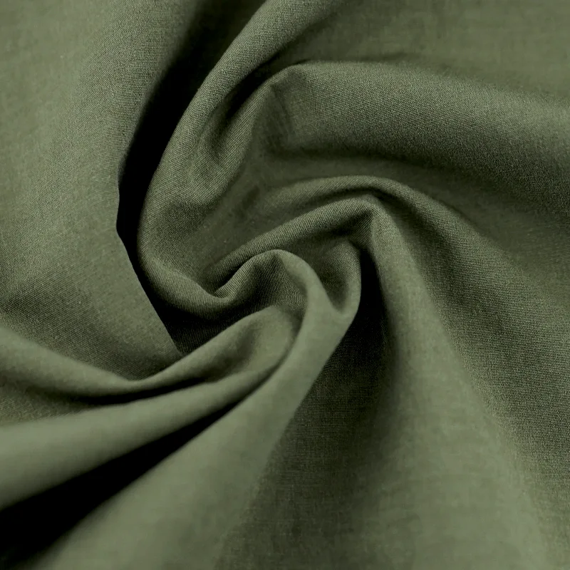 Macro texture of draped olive green woven cotton fabric swirled into soft folds